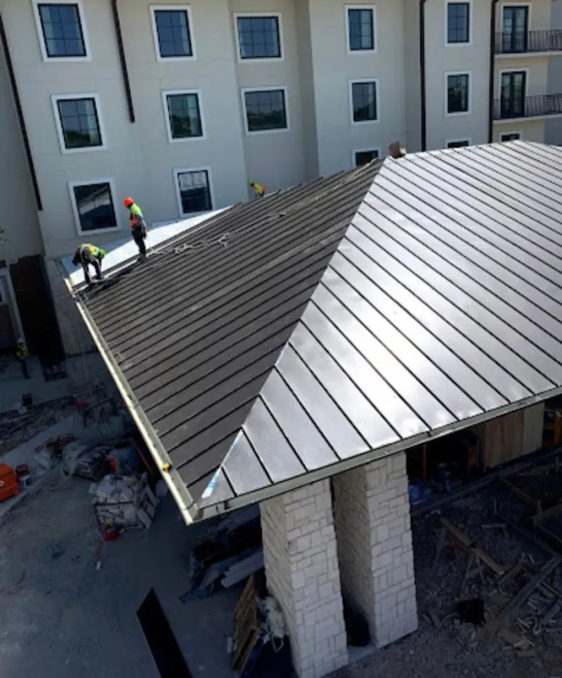 Crew installing standing seam metal roof panels on a commercial project in Gardner